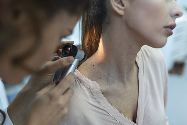 Dermatologue vérifiant un grain de beauté